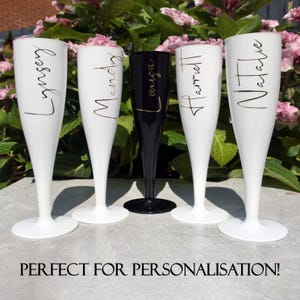 May include: Four white champagne flutes and one black champagne flute, each featuring a unique name in gold cursive script. The names displayed are Lynsey, Mandy, Louisa, Harriet, and Natalie. The text PERFECT FOR PERSONALISATION is below.