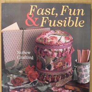 May include: A book titled "Fast, Fun & Fusable" with a NoSew Crafting subtitle. The cover features a floral patterned fabric box with tassels, pencils in a fabric container, and red roses.