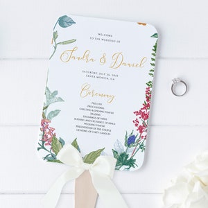 Puede incluir: Un abanico de programa de boda blanco con un diseño floral y una cinta blanca. El programa enumera el orden de la ceremonia para la boda de Sandra y Daniel el 25 de julio de 2025 en Santa Mónica, California.
