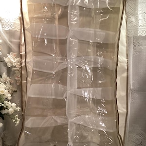 May include: A clear plastic shoe storage organizer with a beige fabric border and a white mesh interior. The organizer has 12 compartments and is labeled with the number "89".