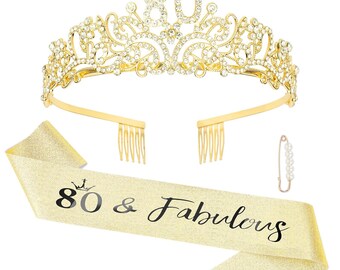 May include: A gold-colored tiara with the number 80 in the center, adorned with clear rhinestones. A matching sash with the text "80 & Fabulous" and a pearl-studded safety pin complete the celebratory set. Perfect for an 80th birthday celebration.