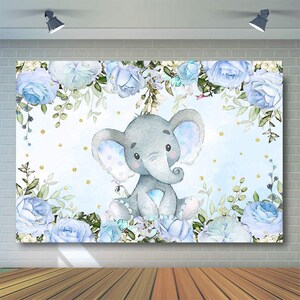 Op de afbeelding: Een lichtblauwe achtergrond met een aquarel-illustratie van een grijze olifant omringd door blauwe rozen en groene bladeren. Goudkleurige glitterpunten zijn over de hele achtergrond verspreid.