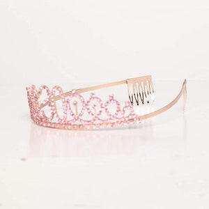 May include: A gold tiara with pink rhinestones and a comb on the back.