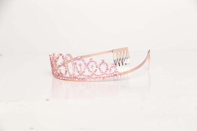 May include: A gold tiara with pink rhinestones and a comb on the back.