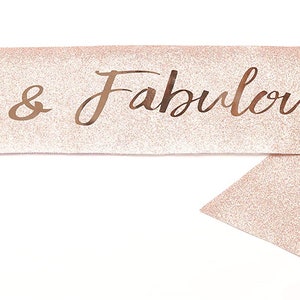 May include: A pink glitter sash with the text "30 & Fabulous" in gold lettering and a crown above the number 30.