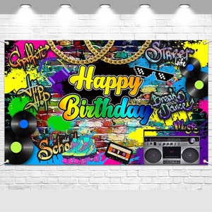 May include: A colorful birthday banner with a graffiti-style design. The banner features the words "Happy Birthday" in large, vibrant letters, along with images of records, roller skates, and a boombox. The background is a brick wall with splashes of paint.