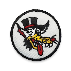 May include: Embroidered patch featuring a cartoon wolf wearing a top hat with a red band. The wolf has a yellow tongue and is holding a yellow and black object in its mouth. The patch has a white background and a black border.