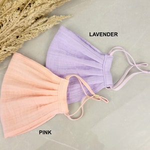 May include: Two fabric face masks, one pink and one lavender, with adjustable straps. The masks are made of a soft, breathable material.