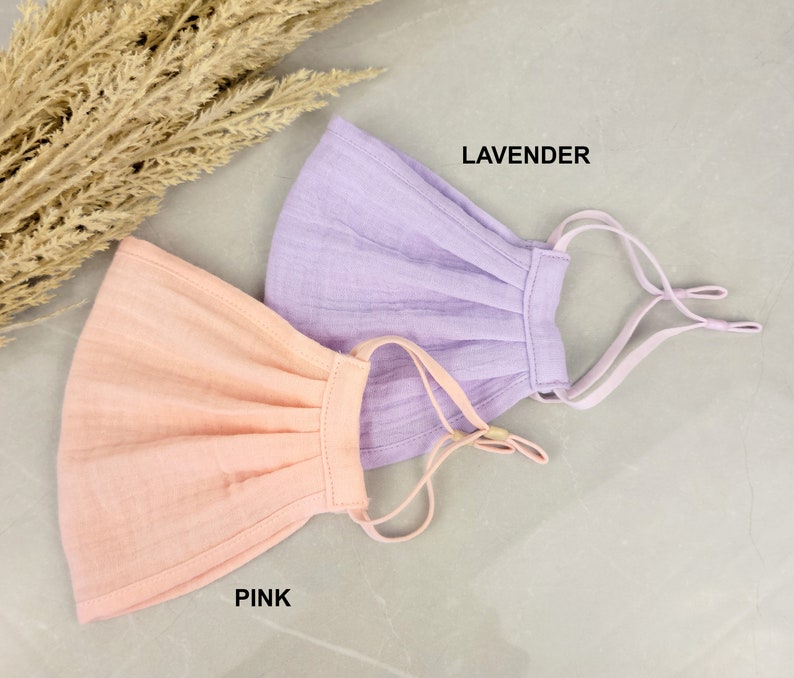 May include: Two fabric face masks, one pink and one lavender, with adjustable straps. The masks are made of a soft, breathable material.