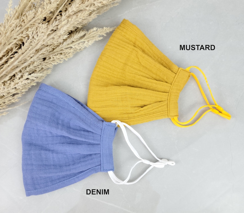 May include: Two fabric face masks, one mustard yellow and one denim blue, with adjustable elastic ear loops. The masks are made of a soft, breathable material.