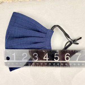 May include: A navy blue fabric face mask with adjustable ear loops. The mask is approximately 5 inches wide.