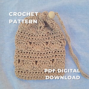 Puede incluir: Una bolsa de ganchillo beige con cierre de cordón y una cuenta de madera. La bolsa presenta un patrón texturizado y las palabras "CROCHET PATTERN" y "PDF DIGITAL DOWNLOAD" en blanco.