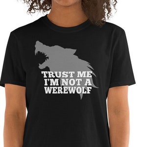 May include: Black t-shirt featuring a gray wolf silhouette with the text "TRUST ME I'M NOT A WEREWOLF" in white. The shirt is a short-sleeved crew neck.