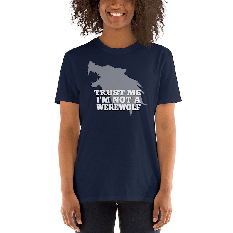 May include: Navy blue t-shirt featuring a gray wolf graphic with the text "TRUST ME I'M NOT A WEREWOLF" in white. The shirt is a short-sleeved crew neck.