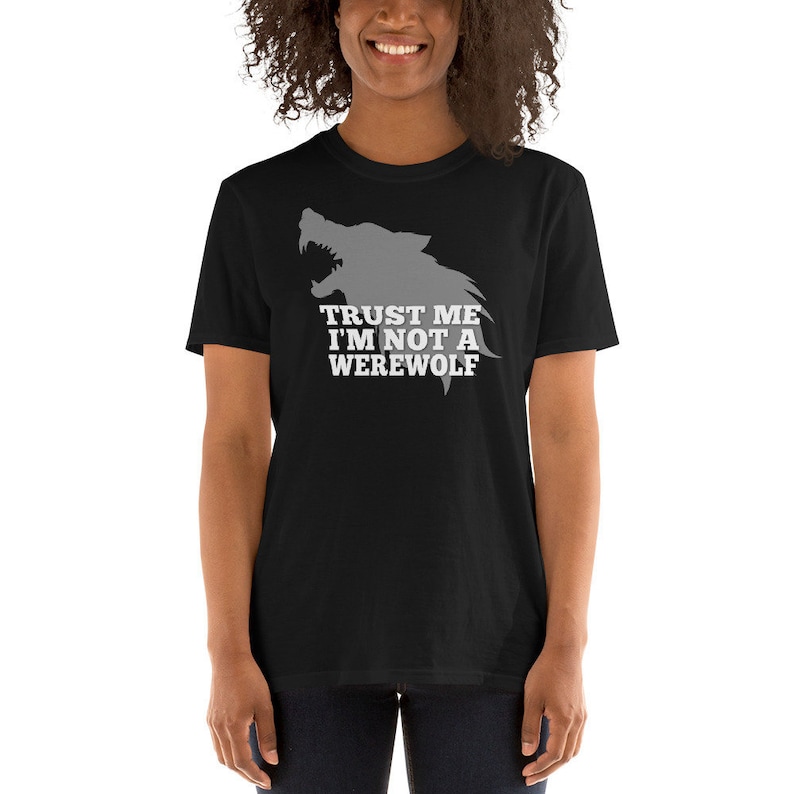 May include: Black t-shirt featuring a gray wolf silhouette with the text "TRUST ME I'M NOT A WEREWOLF" in white. The shirt is a short-sleeved crew neck.