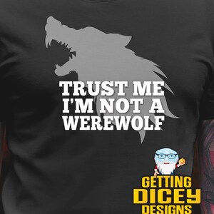 May include: Black t-shirt with a gray werewolf silhouette and the text "TRUST ME I'M NOT A WEREWOLF" in white. The shirt also features a small logo with a cartoon character and the words "GETTING DICEY DESIGNS" in yellow.