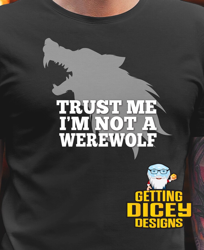 May include: Black t-shirt with a gray werewolf silhouette and the text "TRUST ME I'M NOT A WEREWOLF" in white. The shirt also features a small logo with a cartoon character and the words "GETTING DICEY DESIGNS" in yellow.
