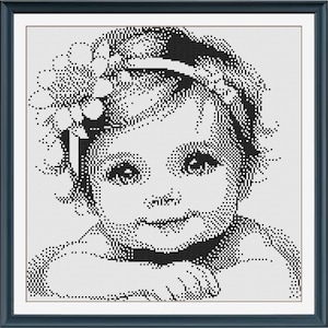 Può includere: Ritratto a punto croce in bianco e nero di una bambina con una fascia floreale. L'immagine è incorniciata in una cornice quadrata blu scuro. La bambina ha un'espressione dolce e guarda direttamente l'osservatore.