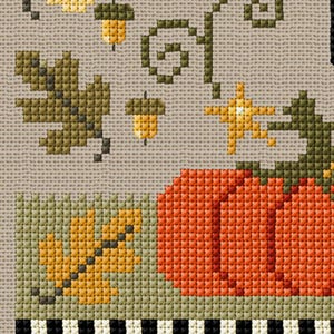 May include: Cross-stitch design featuring autumn elements. An orange pumpkin is next to a green and yellow leaf. Acorns and a star are above the pumpkin. The background is a light tan color with a black and white striped border.