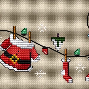 May include: A cross-stitch design depicting Santa's suit and Christmas lights on a washing line. The red suit items, including a hat, jacket, and trousers, are mixed with colourful lights and snowflakes against a beige backdrop.