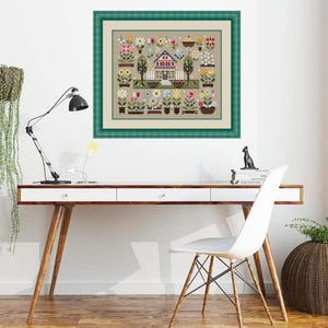 Könnte beinhalten: Ein gerahmtes Kreuzstich-Kunstwerk mit einem malerischen Haus mit rotem Dach und weißem Zaun, umgeben von bunten Blumen in Töpfen. Das Kunstwerk hat einen beigen Hintergrund und einen grünen Rahmen.
