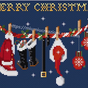 Puede incluir: Un patr&oacute;n de punto de cruz con fondo azul y el texto "Merry Christmas" en amarillo. El patr&oacute;n representa un gorro de Pap&aacute; Noel rojo y blanco, un par de botas negras, un cintur&oacute;n negro y dos guantes rojos y blancos colgados de una cuerda roja y blanca.