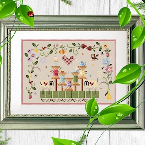 Può includere: Opera d'arte a punto croce in una cornice argentata. Il disegno presenta rocchetti di filo, un cuore, fiori e un gufo. La tavolozza dei colori comprende beige, rosso, verde, giallo e blu. L'opera d'arte ha uno stile di arte popolare.