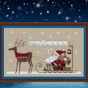 Könnte beinhalten: Kreuzstich-Kunstwerk von Santa Claus in einem von einem Rentier gezogenen Schlitten. Santa, in rotem Anzug und weißem Bart, hält eine Laterne. Der Text "Santa's on his ho ho ho" steht auf einem Banner. Der Hintergrund ist eine Sternennacht.