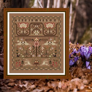 Può includere: Un sampler di punto croce incorniciato con uno sfondo marrone e un design floreale colorato. Il sampler include un cervo, uccelli e un cesto di fiori. L'alfabeto è ricamato nella parte superiore del sampler.