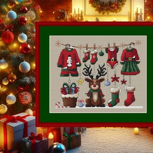 Könnte beinhalten: Ein Kreuzstichmuster mit einem Rentier mit einem rot-weißen Schal, das an einer Wäscheleine hängt, mit verschiedenen weihnachtlichen Kleidungsstücken, darunter ein rot-weißer Weihnachtsmann-Anzug, ein grün-rotes Elfenkostüm und ein rot-weißer Strumpf.