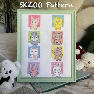 Può includere: Un ricamo a punto croce incorniciato con il testo "SKZOO Pattern" in alto. Il motivo presenta nove diversi personaggi di animali in quadrati colorati.