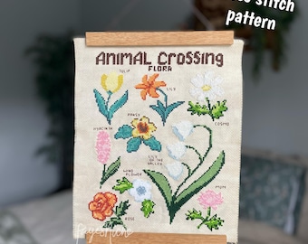 May include: Cross stitch pattern featuring various flowers from Animal Crossing. The design includes a tulip, lily, pansy, hyacinth, windflower, lily of the valley, rose, cosmo, and mum. The text "Animal Crossing Flora" is at the top.