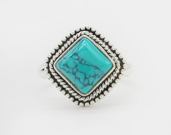 May include: A silver ring with a turquoise gemstone set in a square-shaped bezel. The bezel has a rope-like design around the edge.