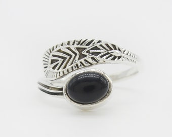 May include: A silver ring with a black stone and a leaf design.