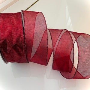 May include: A roll of burgundy sheer ribbon with a shimmery finish. The ribbon is wired and has a satin edge.