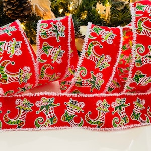 May include: Red and green Christmas ribbon with a white frayed edge. The ribbon features a repeating pattern of elf boots with candy canes and holly.