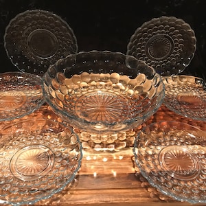 May include: Set of six clear glass plates and a bowl with a bubbled texture. The plates are all the same size and have a scalloped edge. The bowl is larger than the plates and has a wider rim.