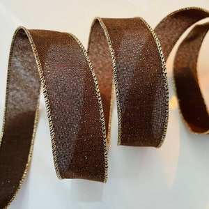 May include: Brown ribbon with gold glitter and gold edges. The ribbon is curled and twisted.
