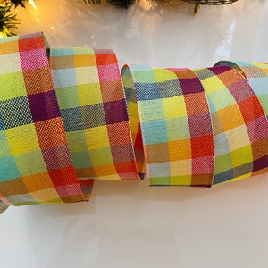 May include: A roll of colorful plaid ribbon with a yellow, orange, red, blue, green, and purple plaid pattern.