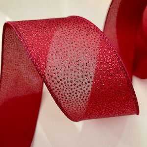 May include: Red ribbon with a subtle shimmer and a fine glitter pattern. The ribbon is woven with a delicate texture.