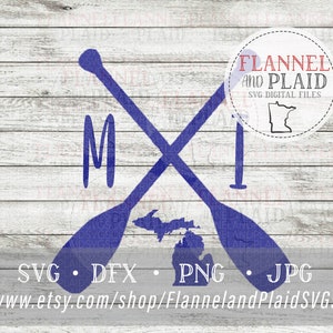 May include: Blue silhouette of two crossed paddles with the state of Michigan and the letter "M" in the center. The image is on a white wood background with the text "Flannel and Plaid SVG Digital Files" in a circle at the top right corner.