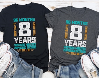 May include: Two t-shirts, one black and one charcoal gray, with the text "96 Months, 8 Years" in white and teal. The shirts are paired with blue jeans and white sneakers. The text also includes the number of days, hours, minutes, and seconds.