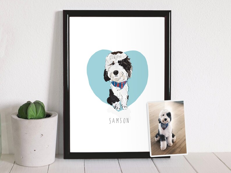 May include: A framed art print featuring a cartoon illustration of a dog named Samson. The dog is black and white with a blue and red patterned bandana, set against a light blue heart. A smaller photo of the dog is also present.