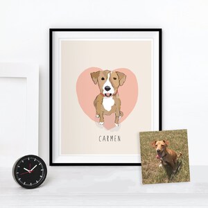 May include: A framed art print featuring a cartoon dog illustration with a pink heart background. The dog is brown and white, wearing a red collar, and the name "CARMEN" is written below. A photo of the dog is next to the framed print.