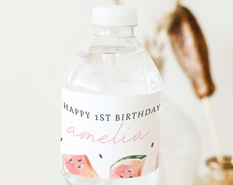 May include: Water bottle label with a white background and black text that reads "Happy 1st Birthday Amelia". The label also features a pink watercolor illustration of watermelon slices.