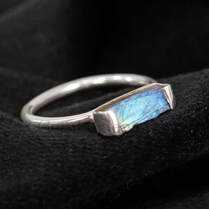 May include: A silver ring with a blue labradorite gemstone. The gemstone is rectangular in shape and has a unique iridescent quality.