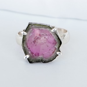 以下が含まれることがあります： ピンクとグリーンのトルマリンの宝石がついたシルバーリング。宝石はシルバーのベゼルにセットされており、ラフで自然な形をしています。