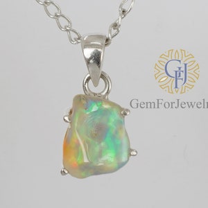 May include: A silver chain necklace with a pendant featuring a raw, iridescent opal stone. The opal is set in a silver bezel and has a green, blue, and yellow colour.
