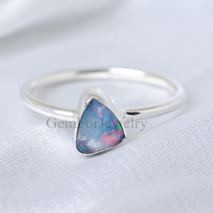 Könnte beinhalten: Ein silberner Ring mit einem dreieckigen Opal-Edelstein. Der Opal hat einen blauen, grünen und rosafarbenen irisierenden Schimmer.