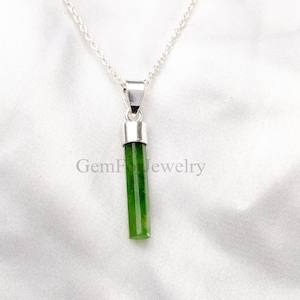 May include: A silver chain necklace with a green jade pendant. The pendant is a long, thin, rectangular shape.
